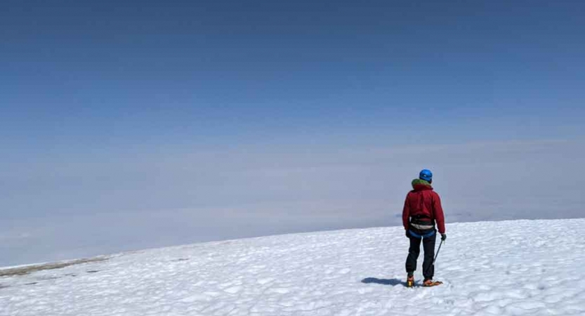 a person stands in a high, snowy field on a mountaineering course with outward bound